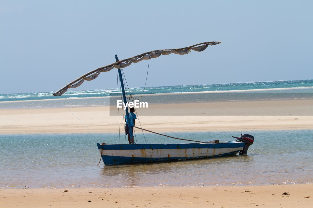 MEN WORKING ON SHORE AGAINST CLEAR SKY