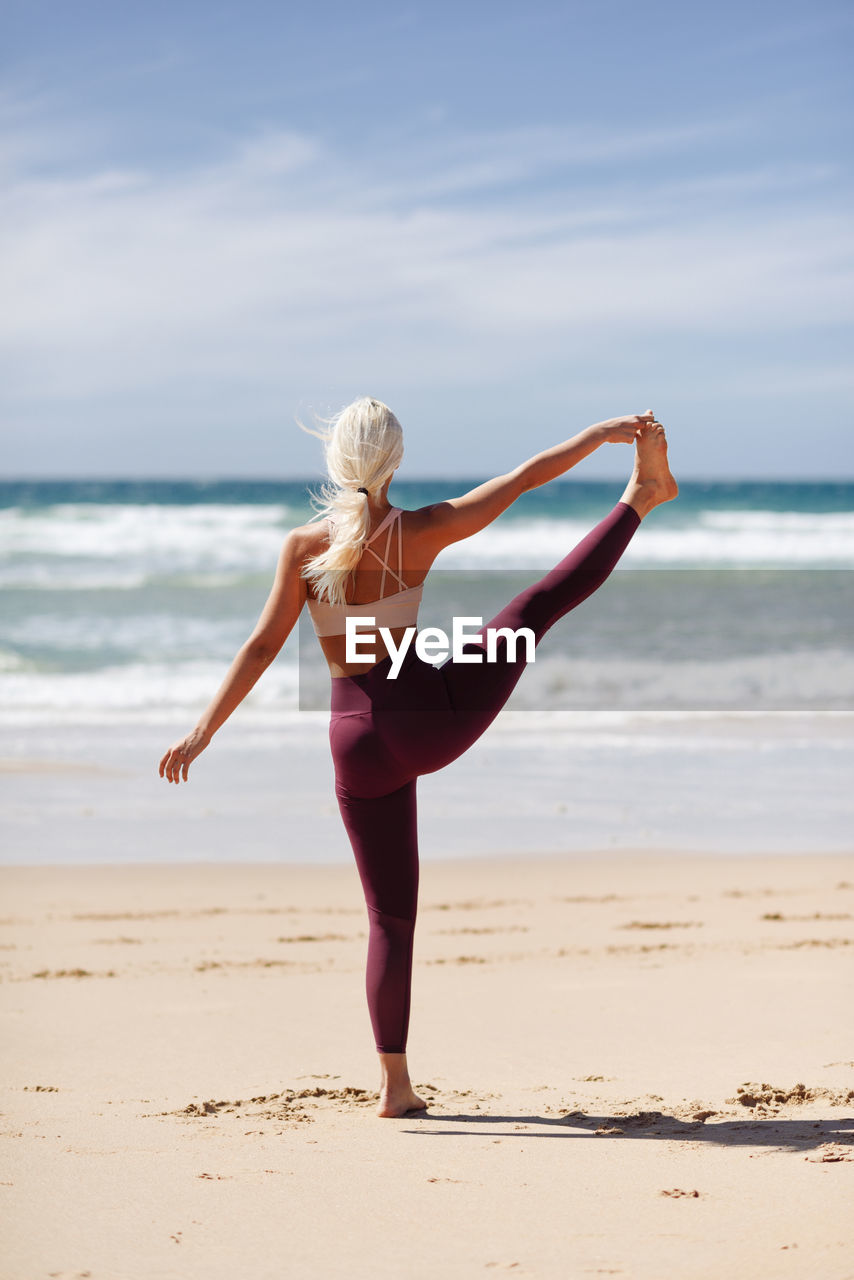 Woman exercising at beach in sunny day