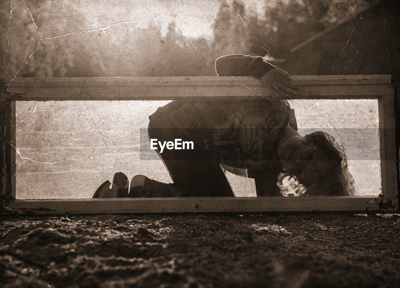 Silhouette boy seen through glass outdoors