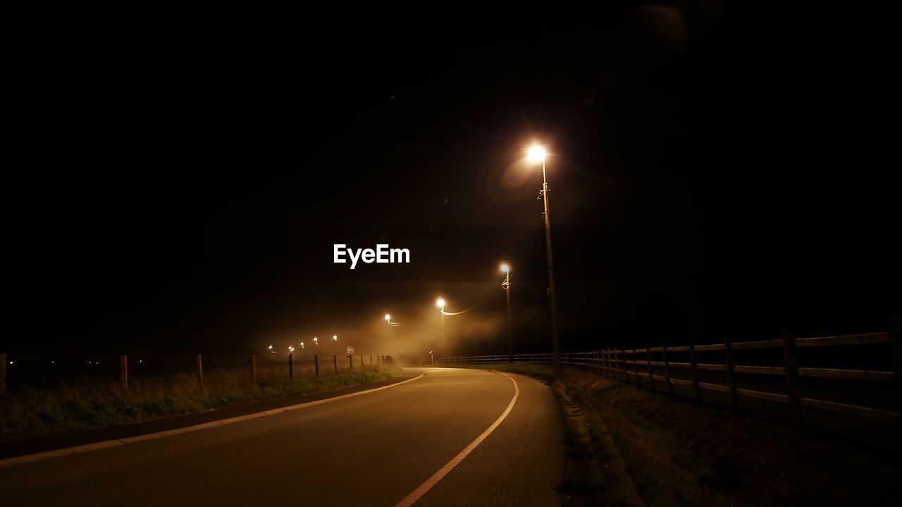 VIEW OF ILLUMINATED STREET LIGHTS AT NIGHT