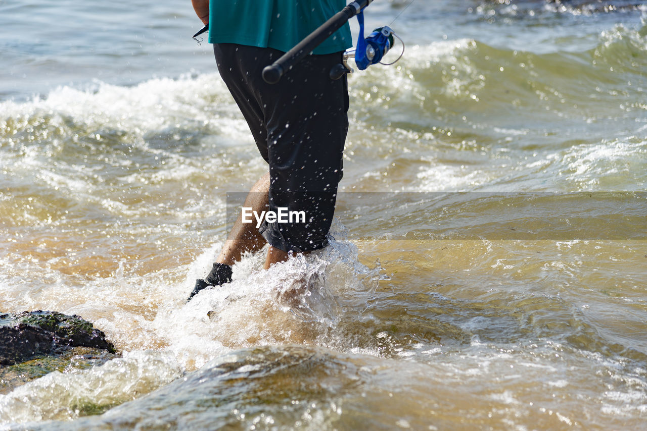 Low section of man splashing water in sea