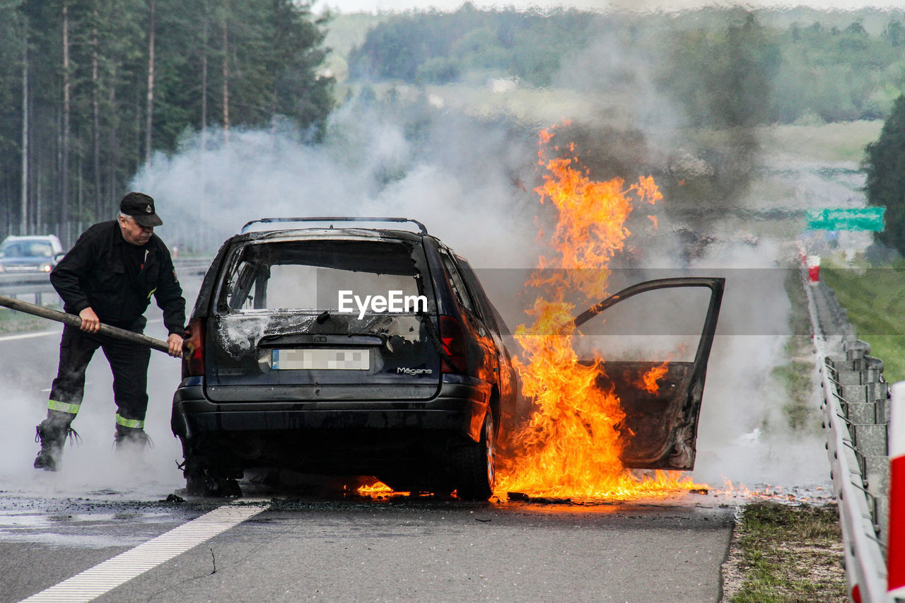 MAN STANDING BY CAR ON ROAD