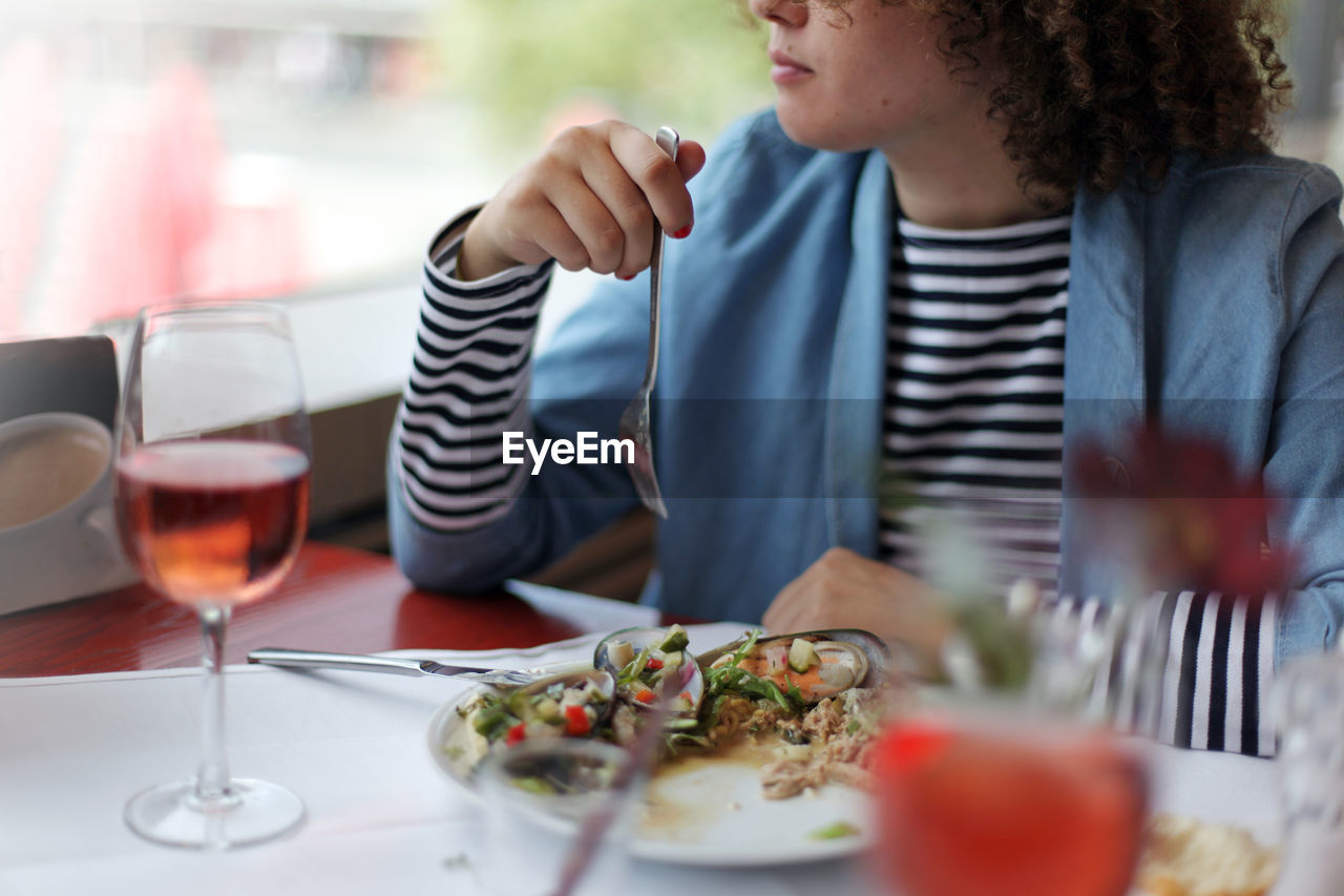 Midsection of woman having food in plate at restaurant