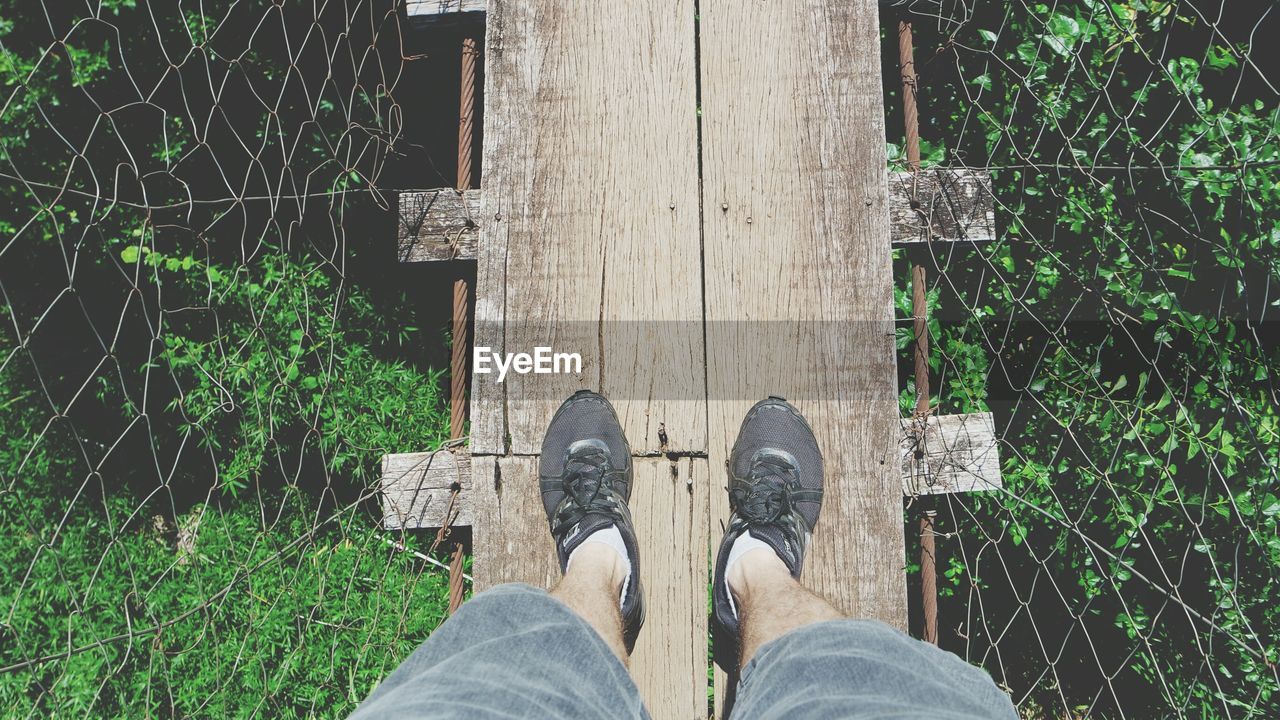 LOW SECTION OF MAN STANDING ON WOODEN POST