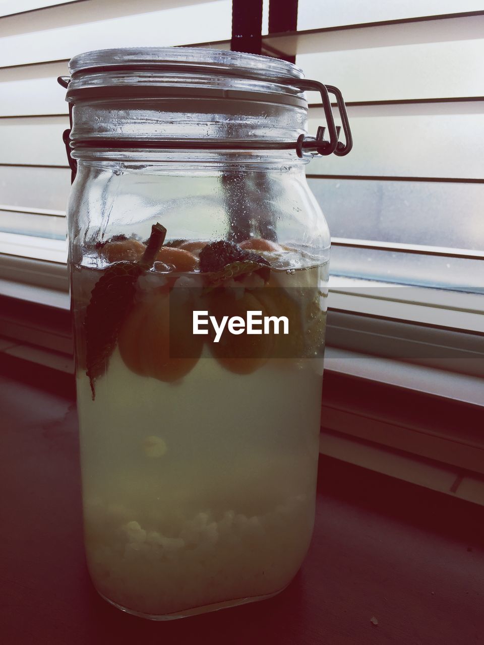 Close-up of juice with apricots on window sill