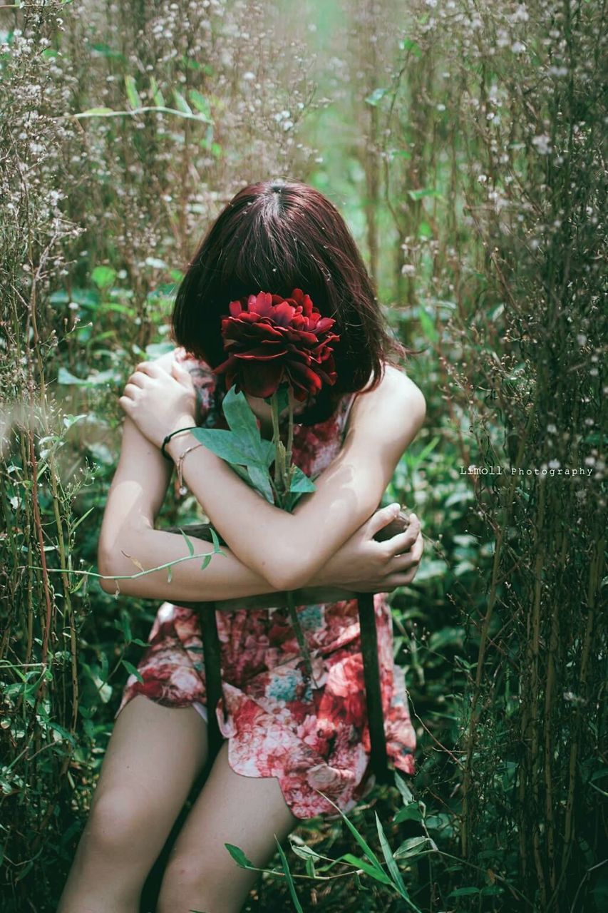 YOUNG WOMAN HOLDING FLOWER IN HAND