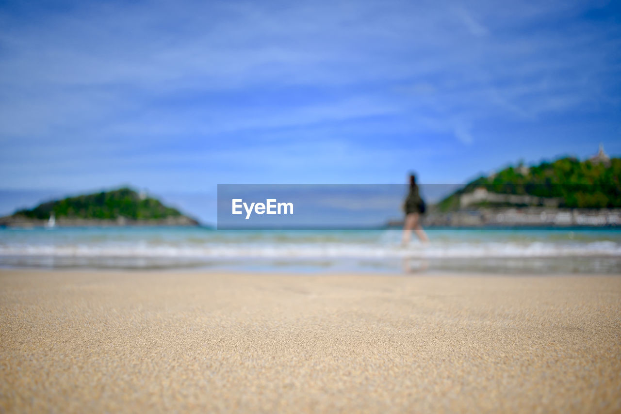 MAN AT BEACH AGAINST BLUE SKY