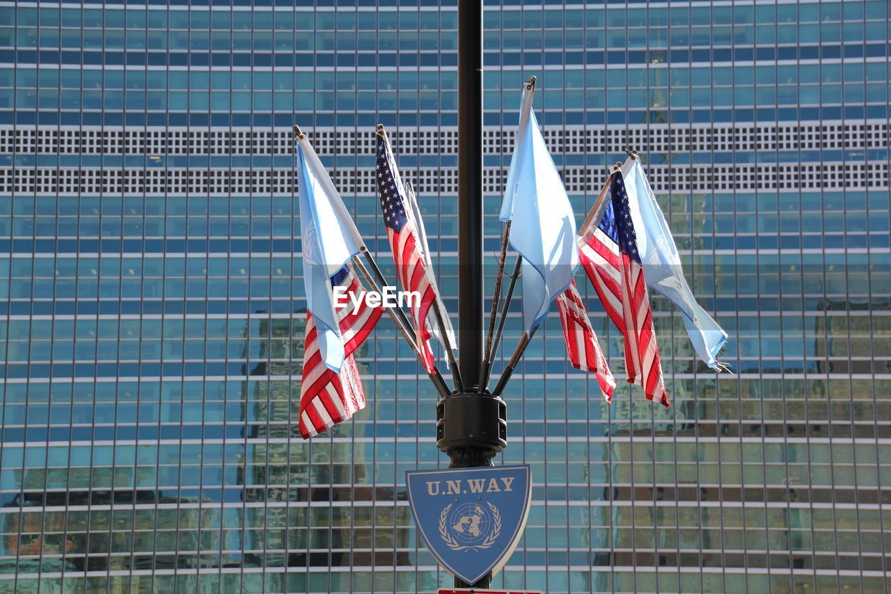 Low angle view of american flags and united nations flags against modern building