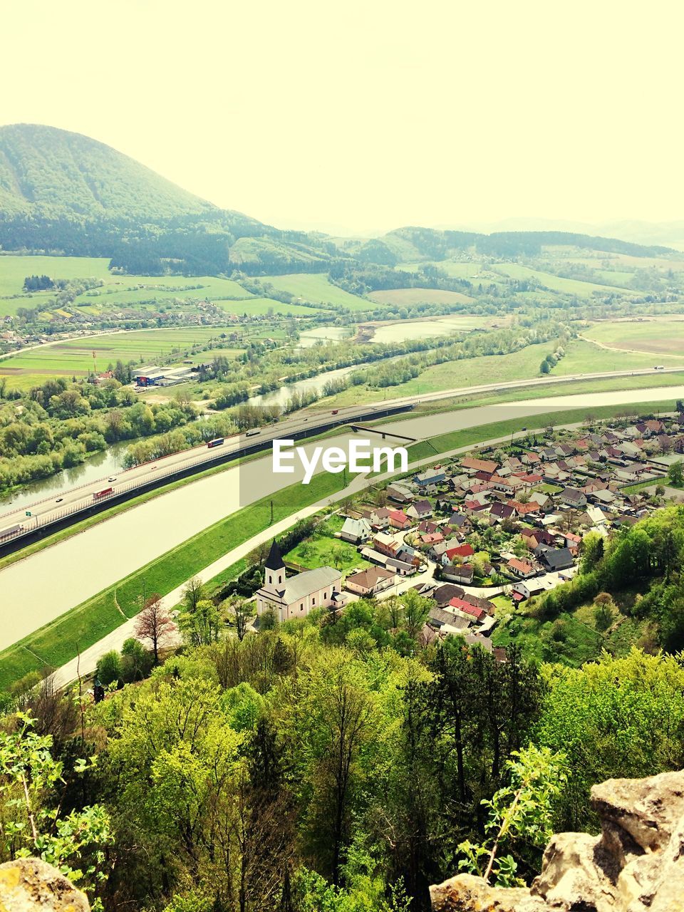 High angle view of canal amidst town and mountains against clear sky