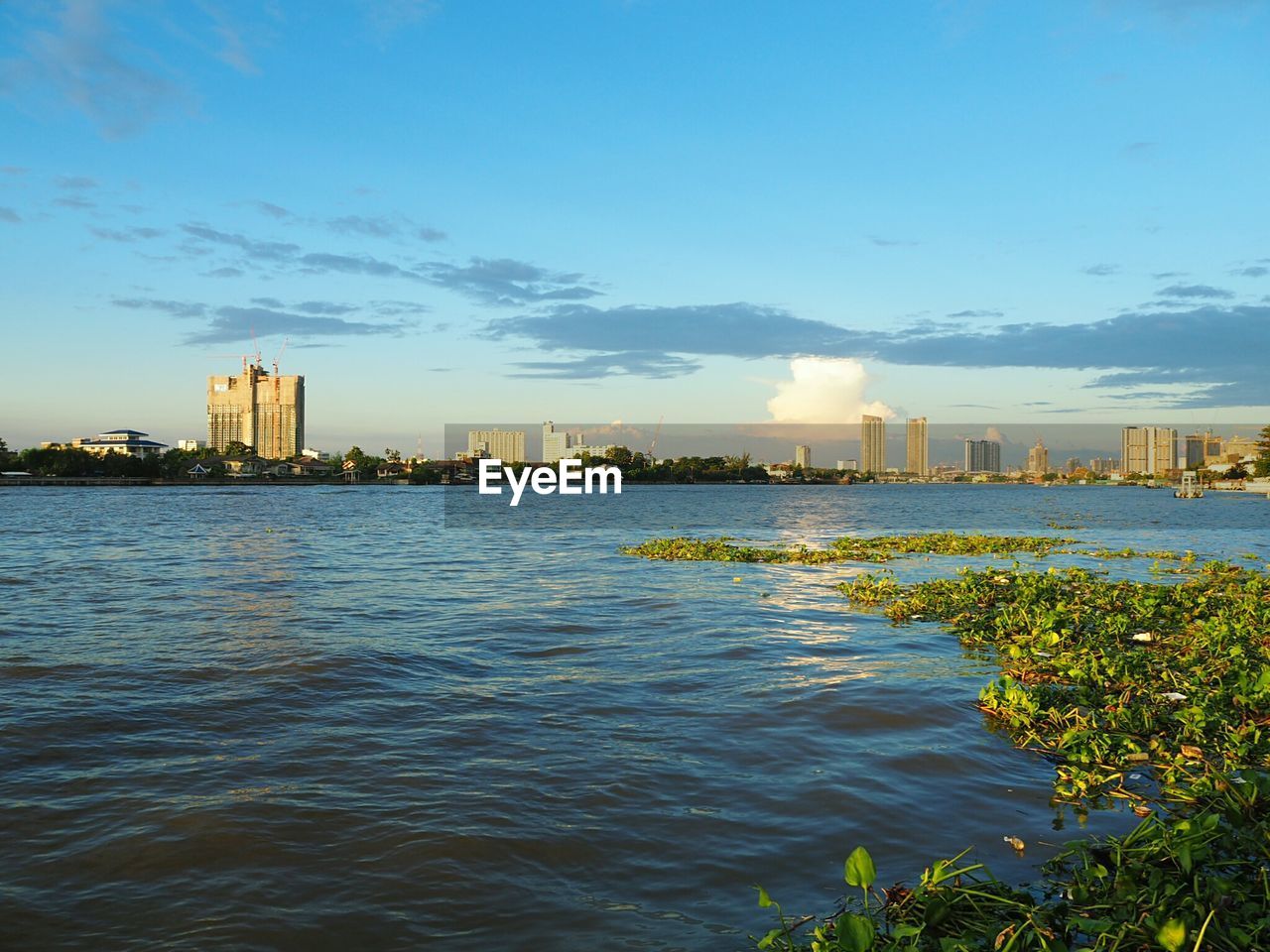 VIEW OF CITYSCAPE BY RIVER AGAINST SKY