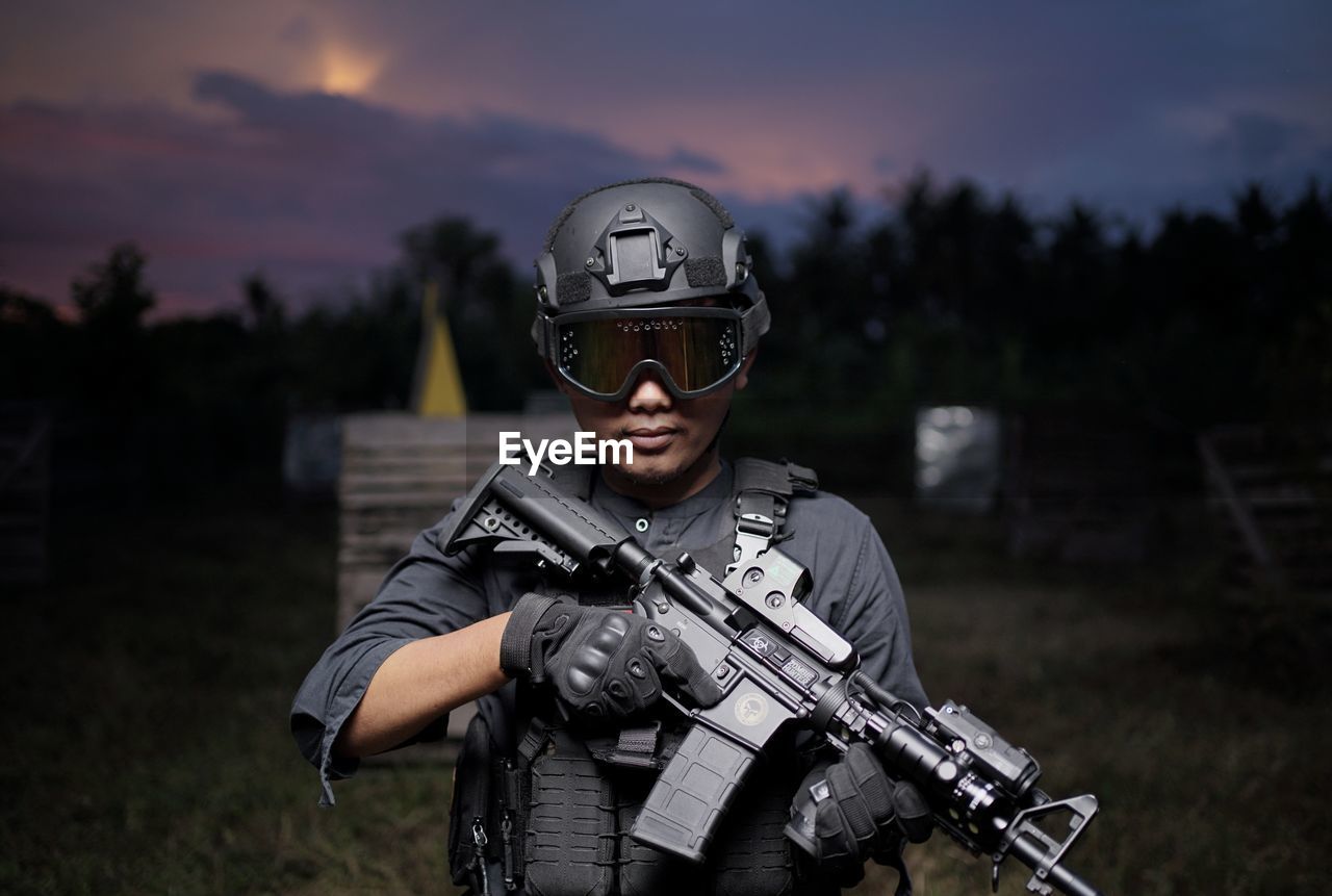 Rear view of man standing on field with weapons and equipment at night