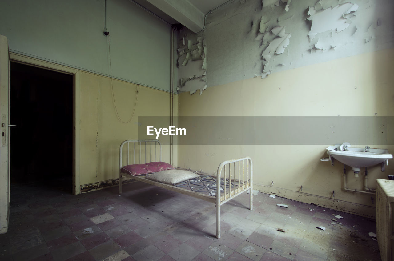 Empty bed in abandoned prison cell