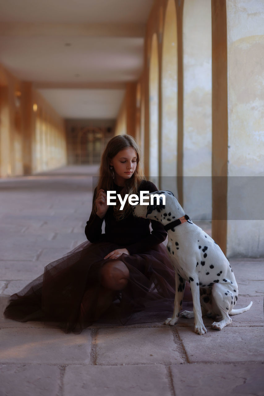 Portrait of young woman sitting on the floor with dalmatian