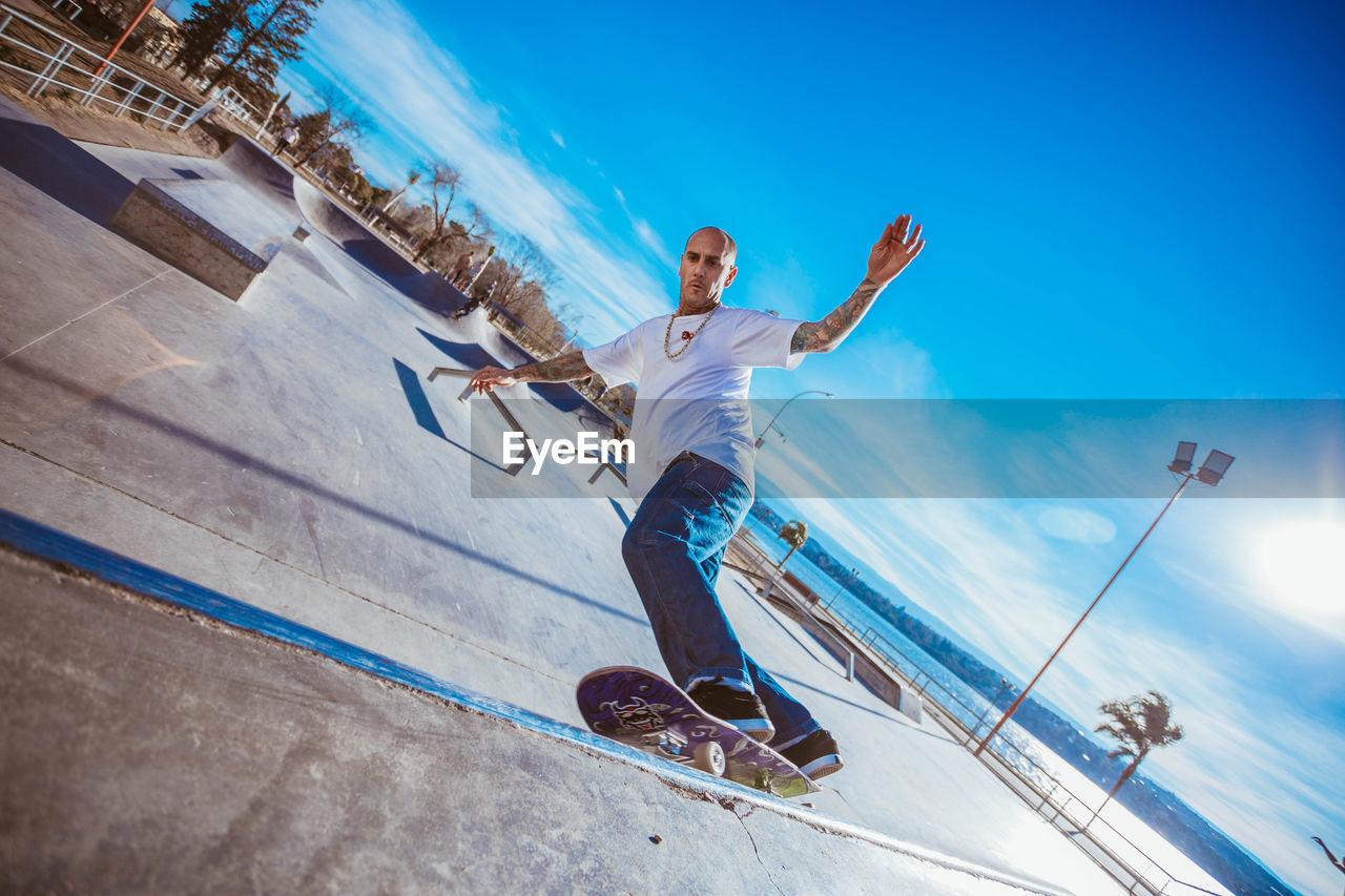 Man skateboarding against blue sky during sunny day