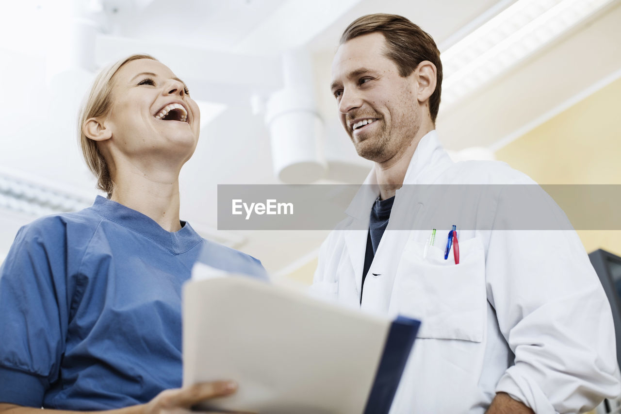 Happy doctor with nurse holding report in hospital