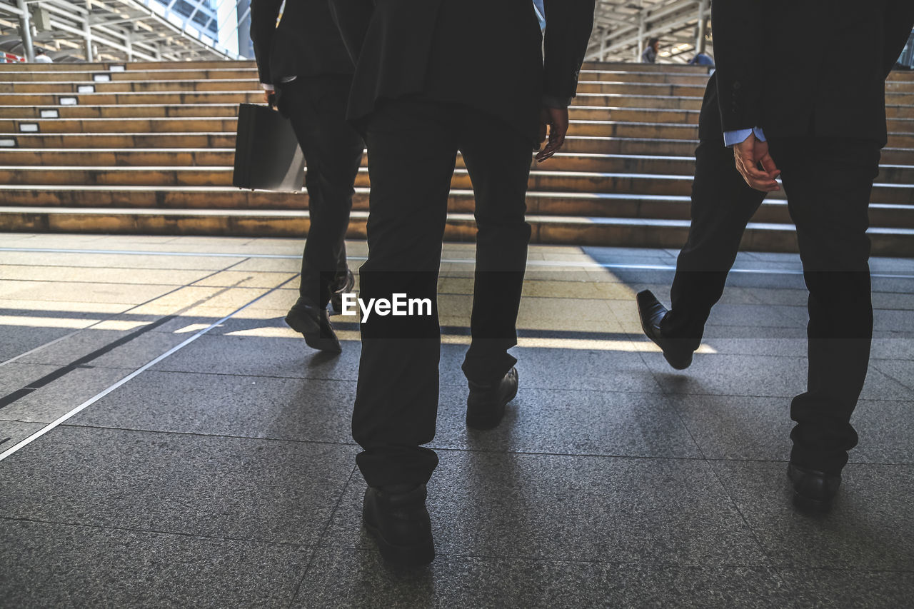 Low section of businessmen walking towards steps