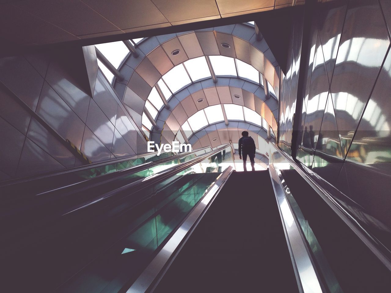 Low angle view of man standing on escalator in building