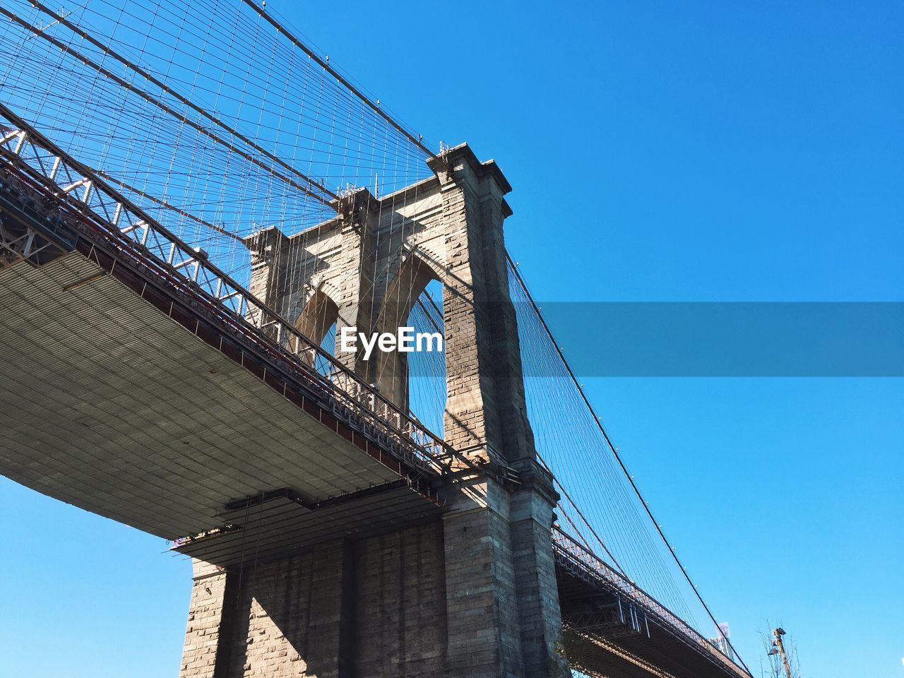 LOW ANGLE VIEW OF SUSPENSION BRIDGE AGAINST CLEAR BLUE SKY