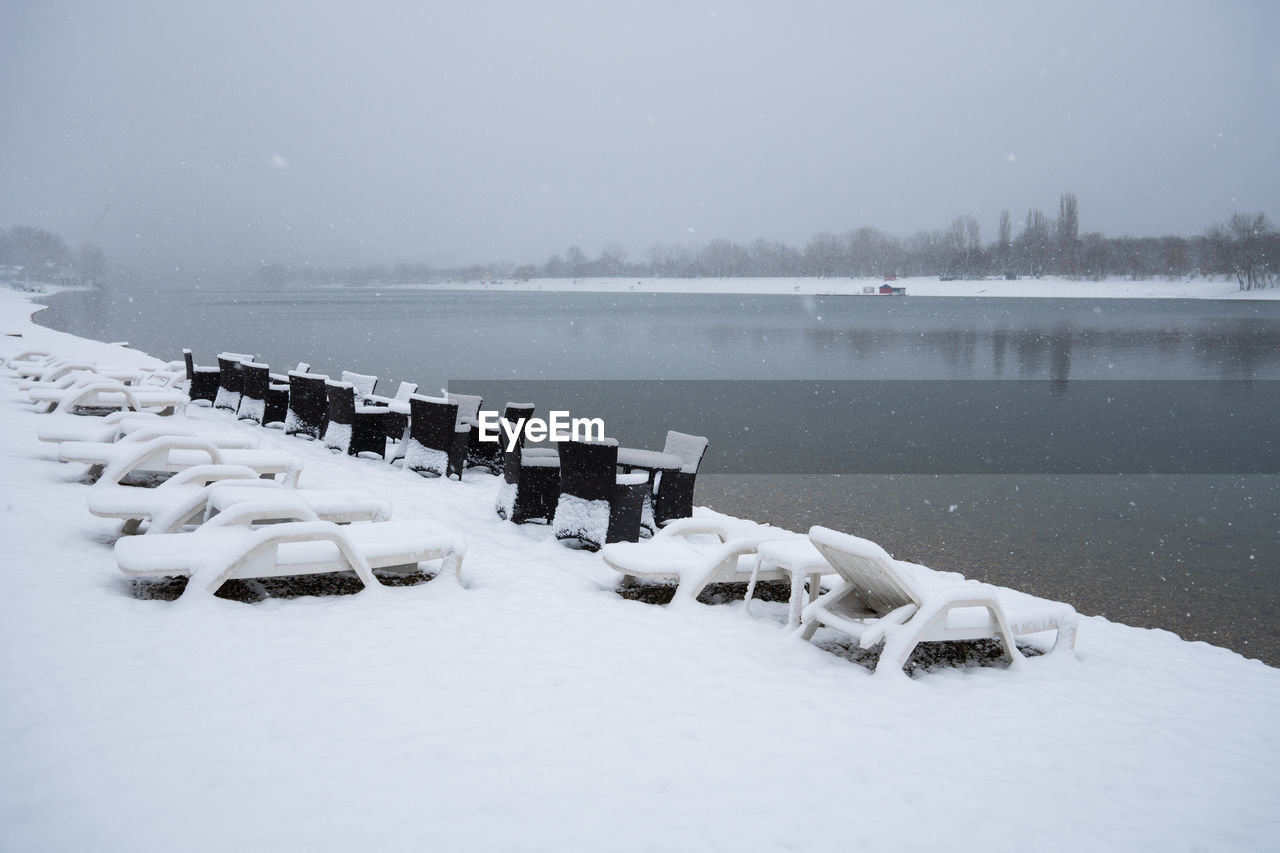 winter, snow, cold temperature, water, freezing, nature, environment, scenics - nature, beauty in nature, tranquility, tranquil scene, lake, sky, landscape, frozen, no people, land, blizzard, fog, white, ice, non-urban scene, seat, in a row, outdoors, day, architecture, travel destinations, beach, travel, extreme weather, idyllic, pier, chair, silence