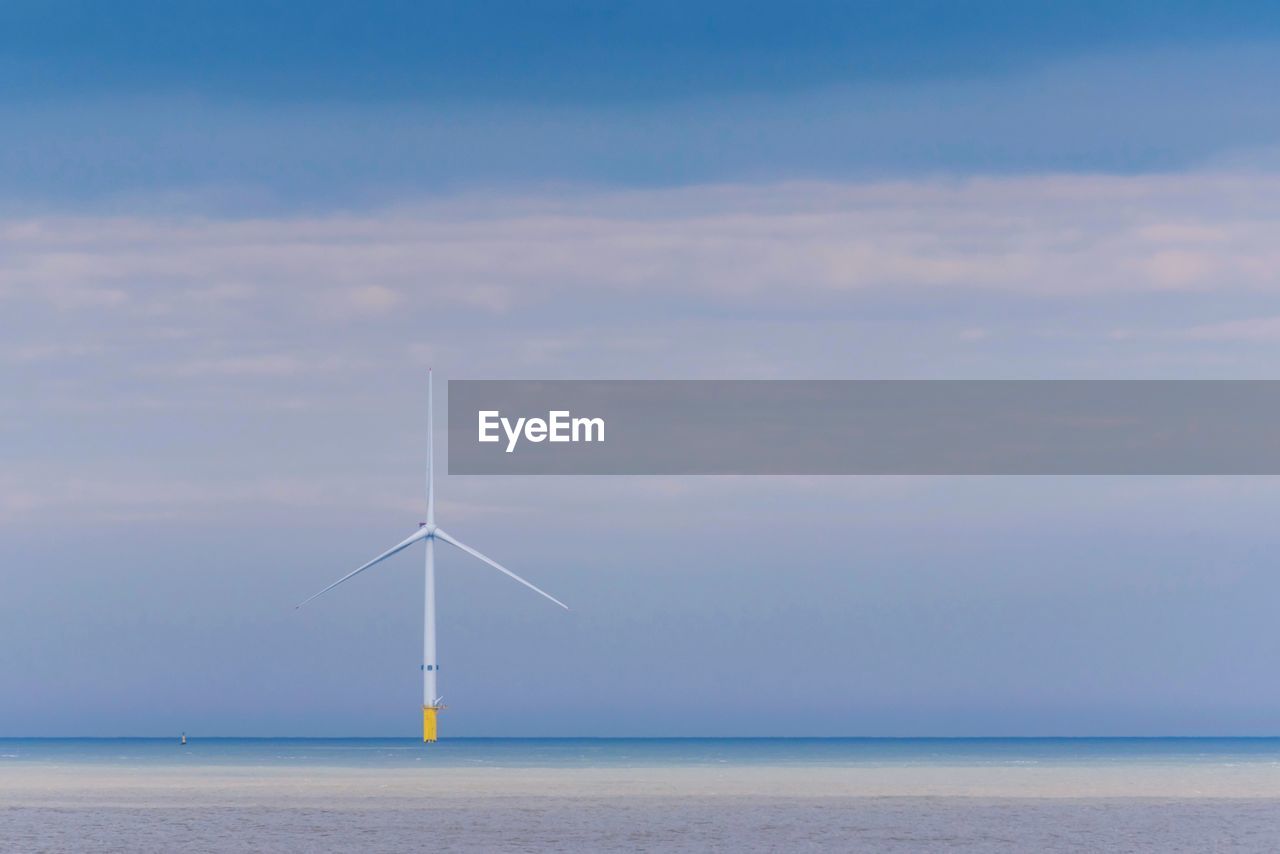 Wind turbines in sea against sky