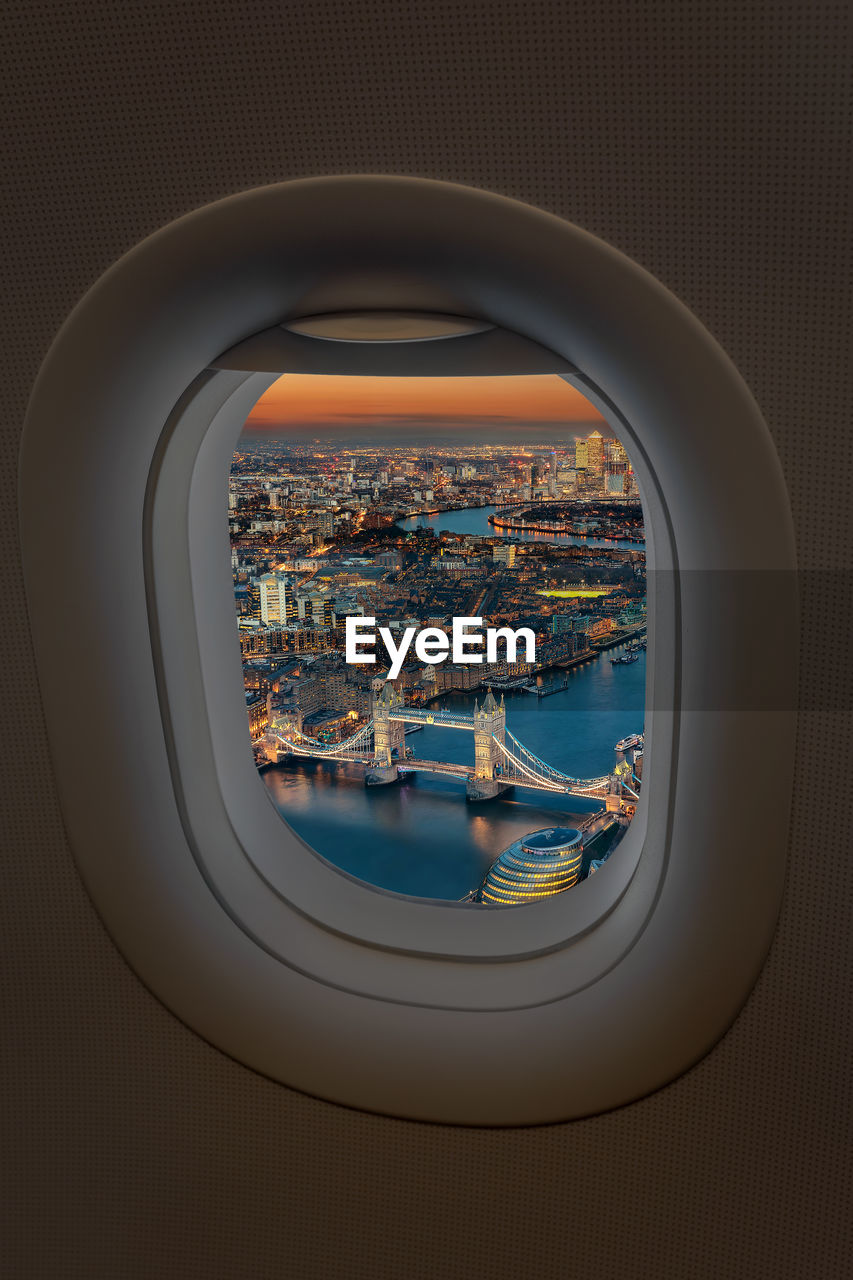 Tower bridge over thames river in city seen through airplane window at dusk