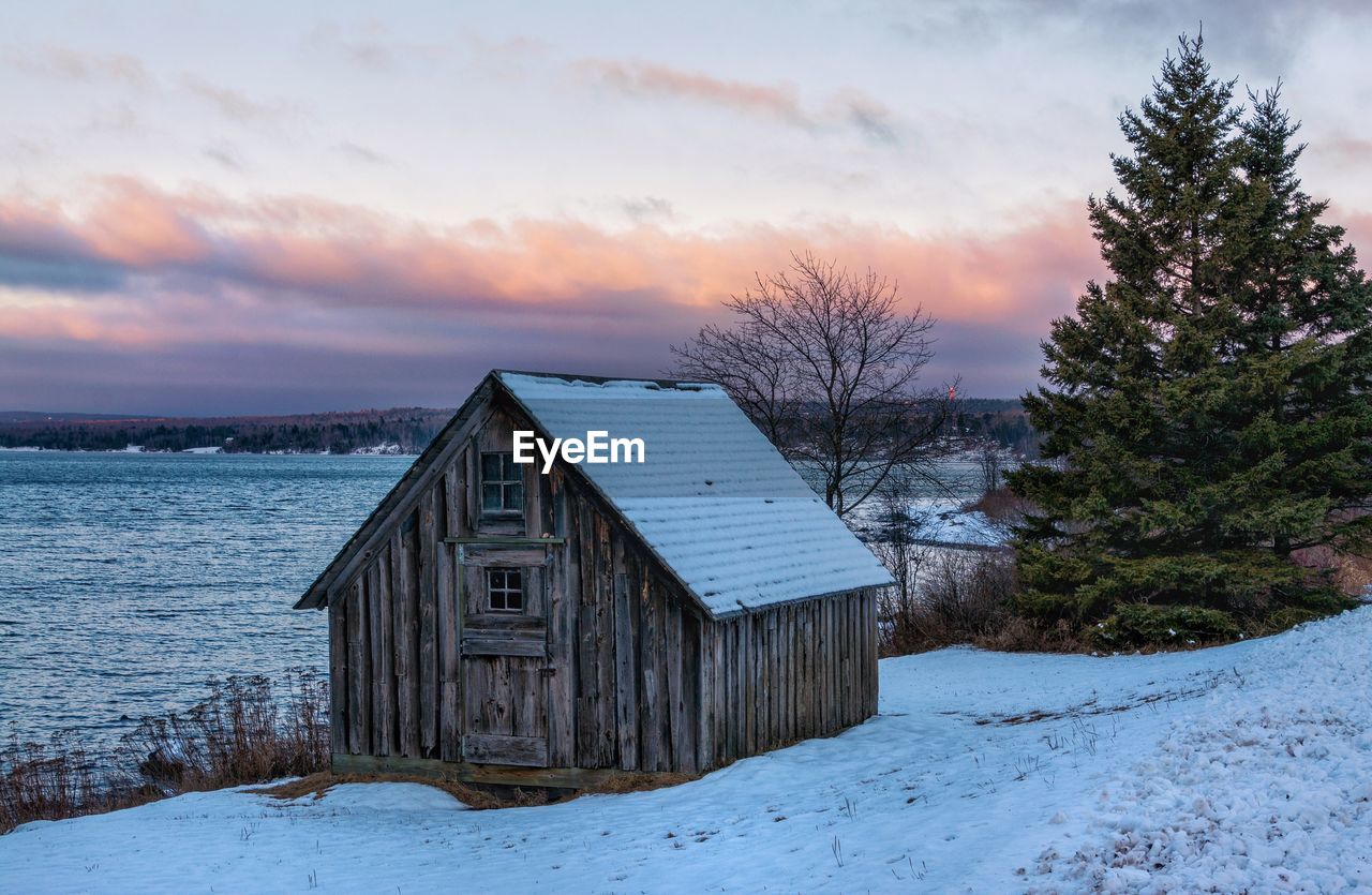 BUILT STRUCTURE BY TREES AGAINST SKY DURING WINTER