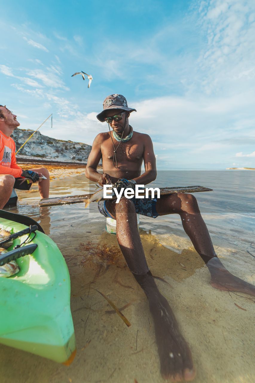 MAN SITTING ON BEACH