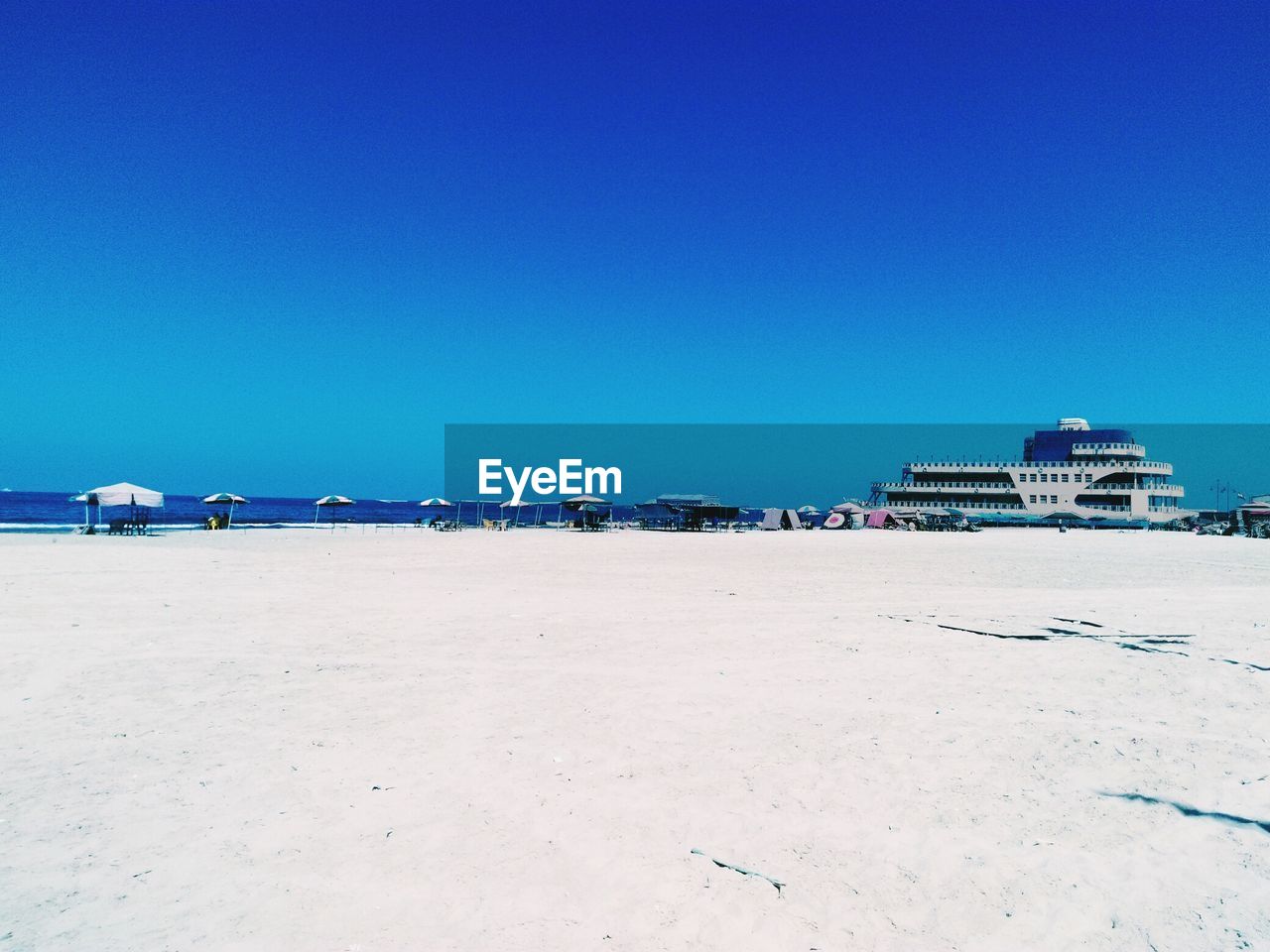 Scenic view of beach against clear blue sky