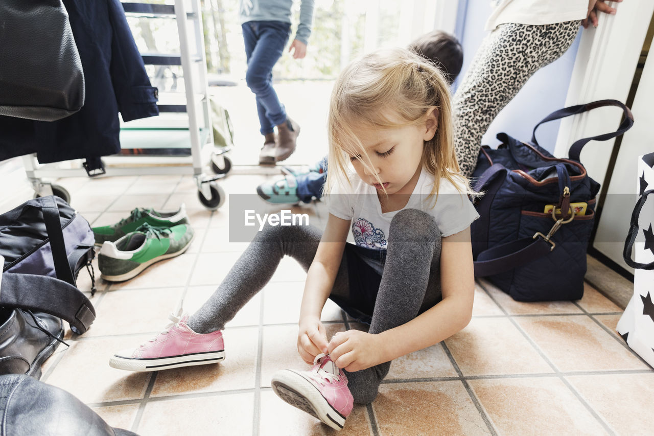 Girl wearing shoe while sitting on floor at day care center