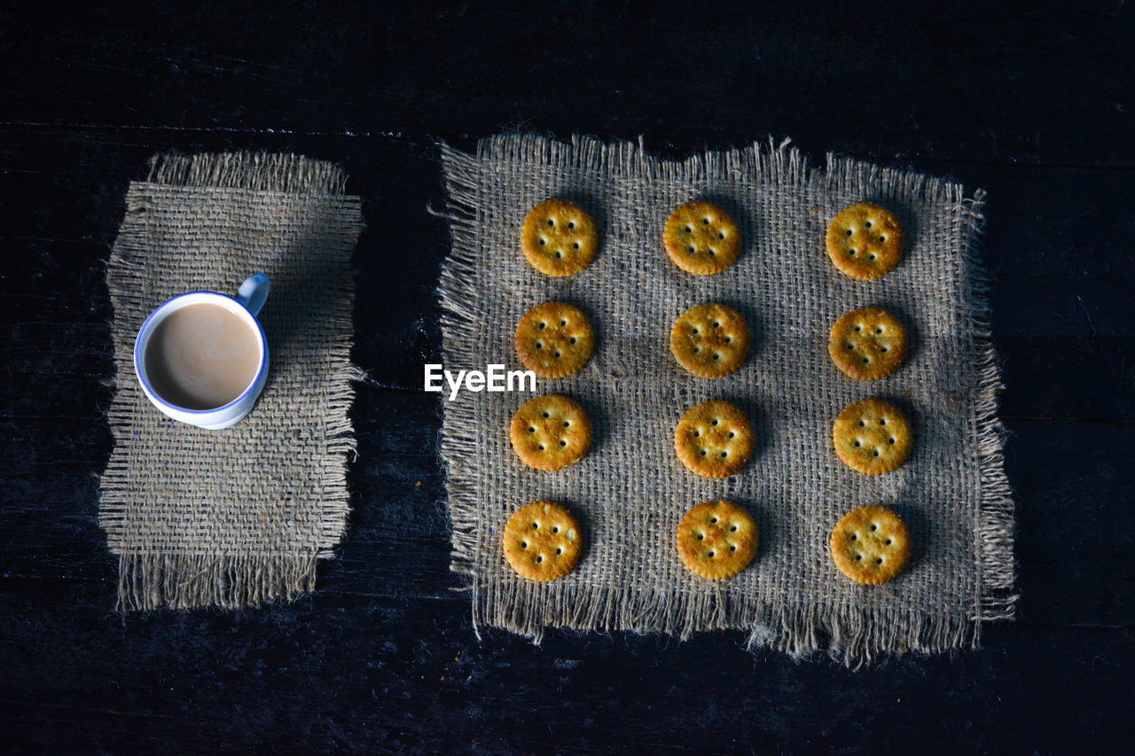 A cup of tea with biscuits on old wooden dark background