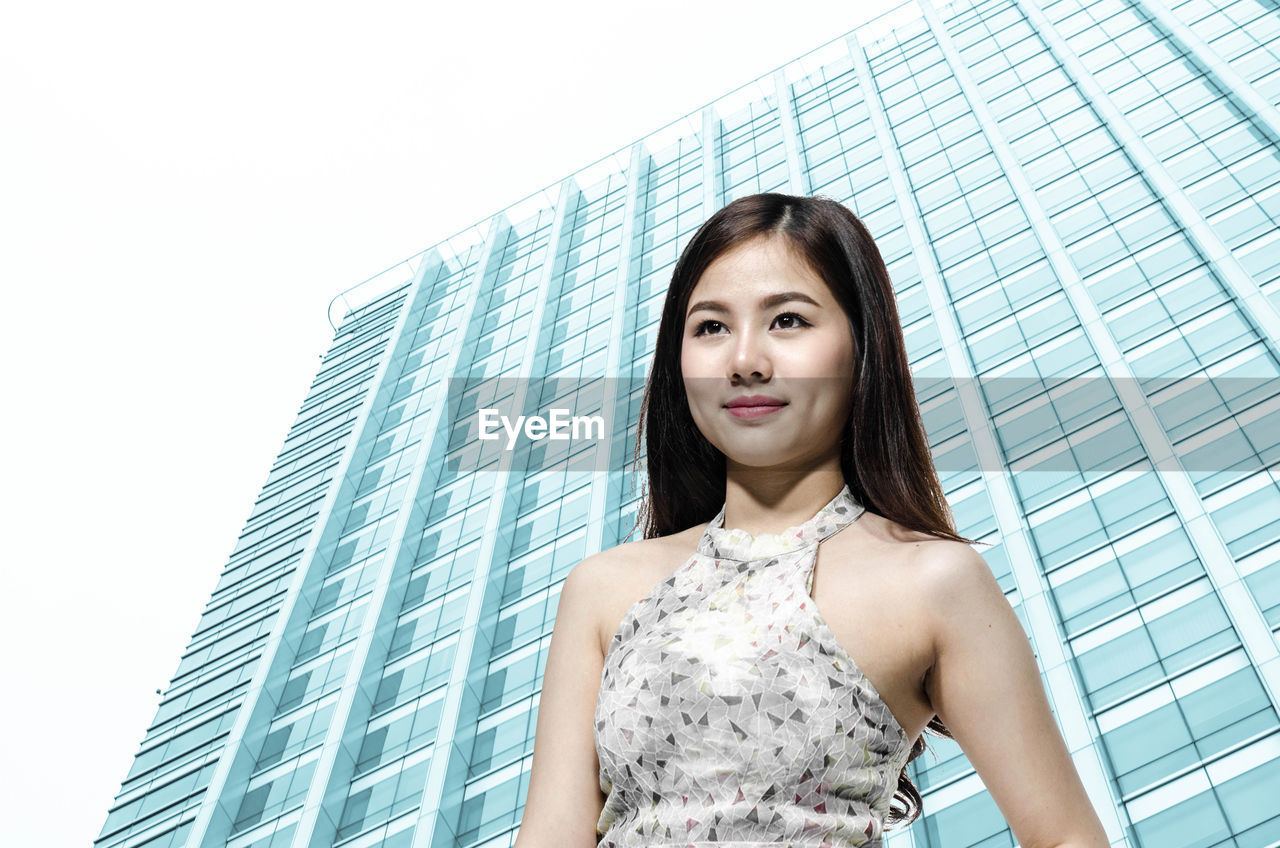 Low angle view of beautiful woman standing against modern building