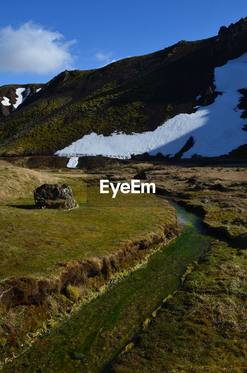 Spring day in iceland with a scenic landscape with a flowing hot spring river.