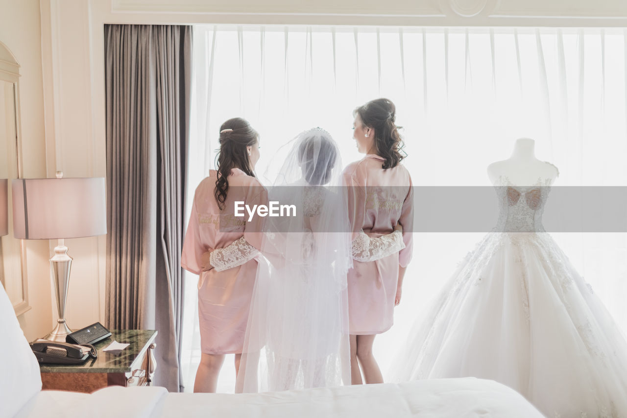 Bride with maids standing at home during wedding ceremony