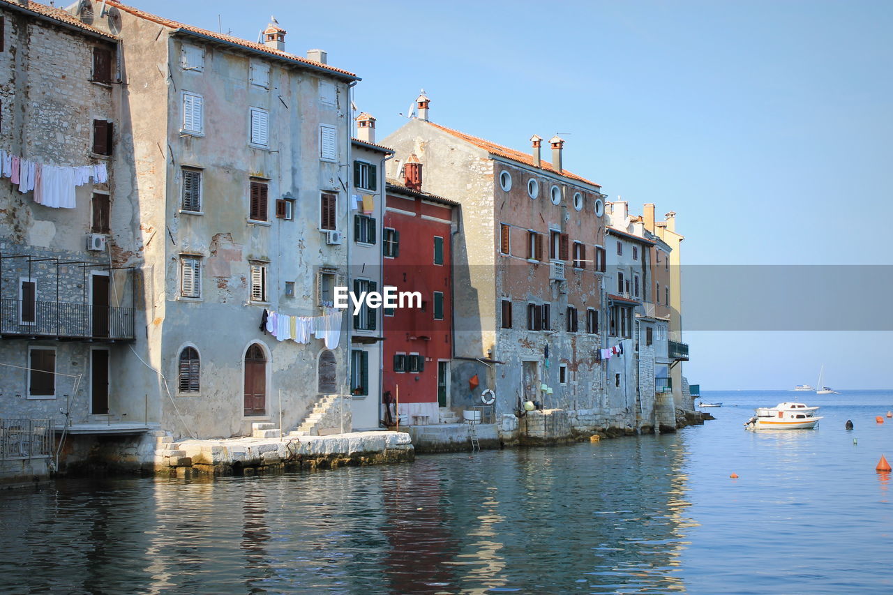 Houses by sea against clear sky