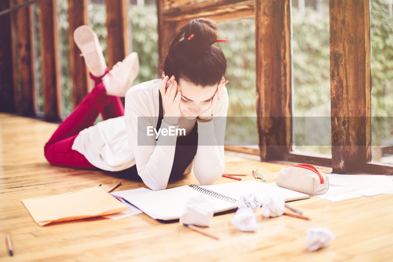 Woman reading book while lying on floor