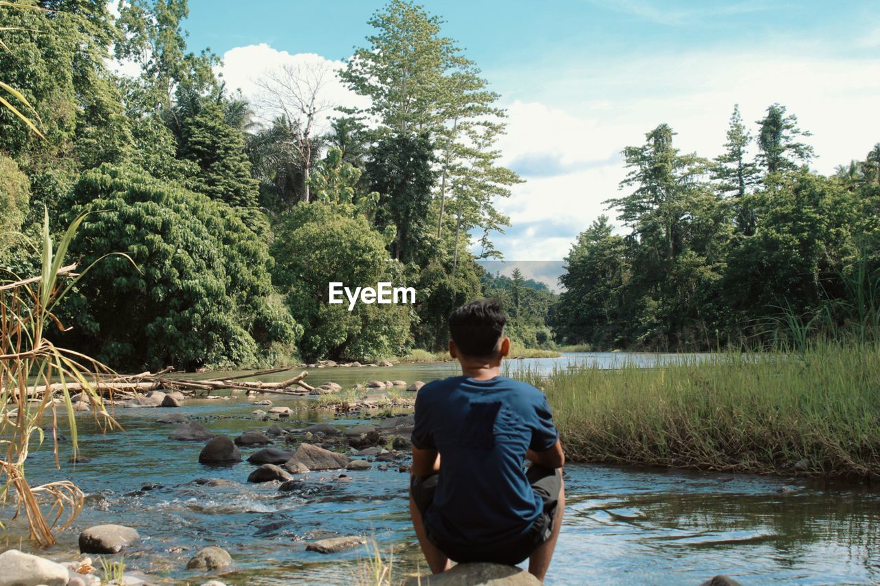 REAR VIEW OF MAN IN LAKE AT FOREST