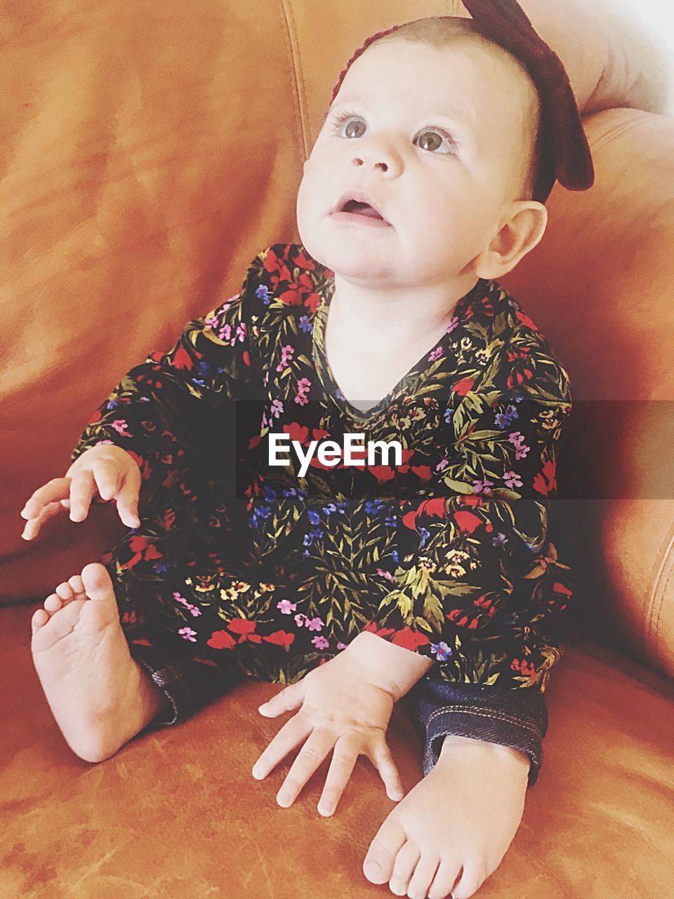 Baby girl looking up while sitting on sofa