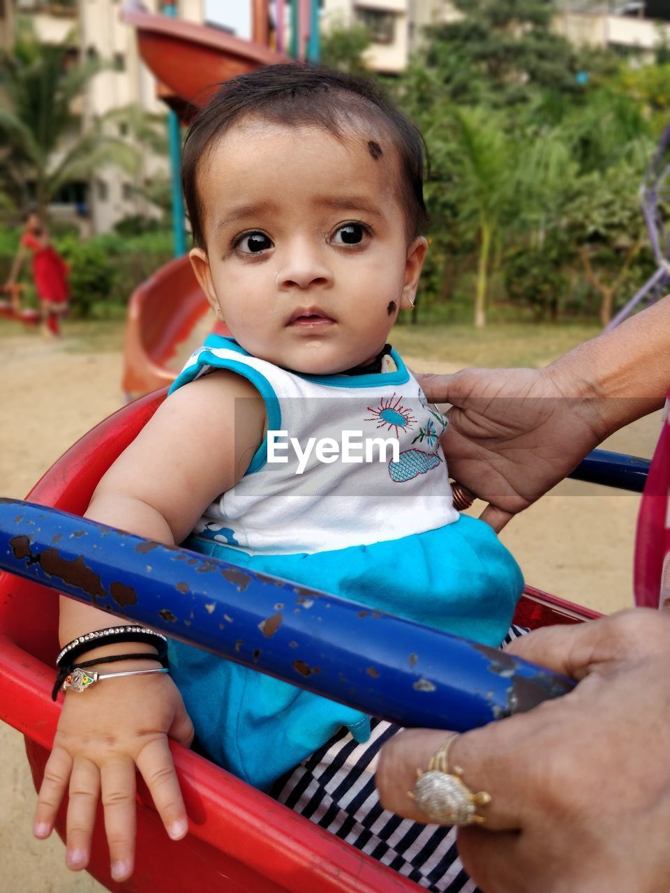 Cropped hand of parent holding daughter sitting on swing