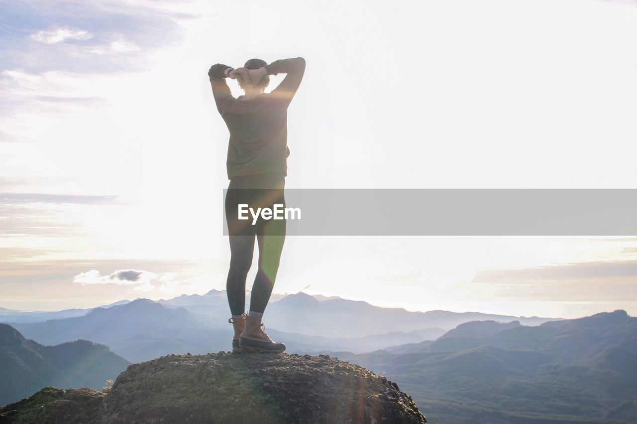 Rear view of woman standing on mountain against sky