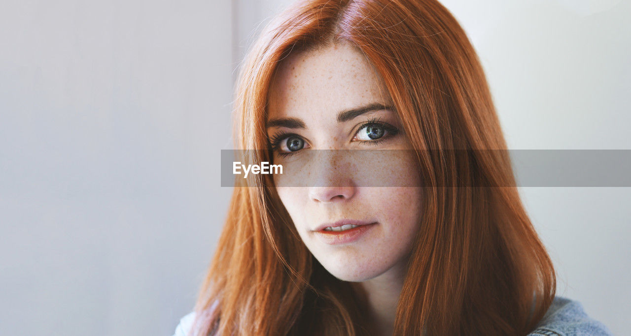 Indoor portrait of young woman with red hair and freckles