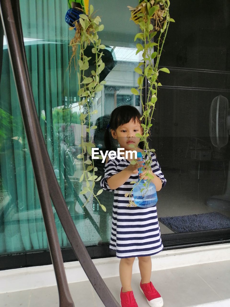 Cute girl spraying water on plant