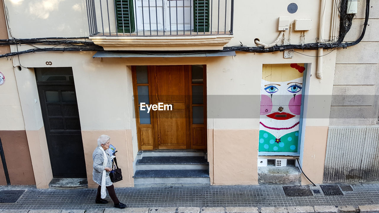 WOMAN STANDING WITH UMBRELLA ON BUILDING