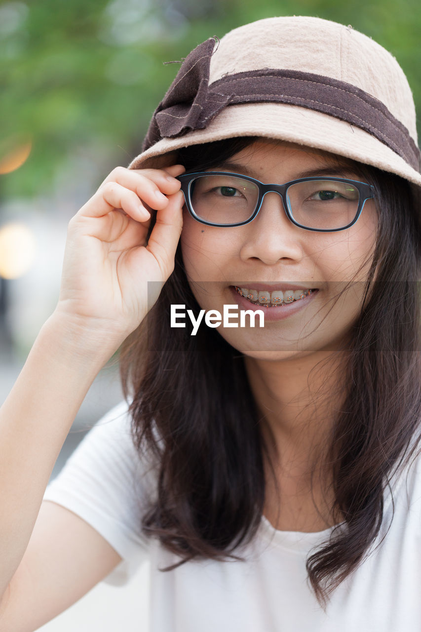 Close-up portrait of smiling young woman wearing hat