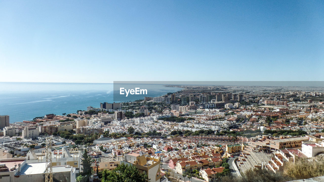 Aerial view of city by sea against clear sky