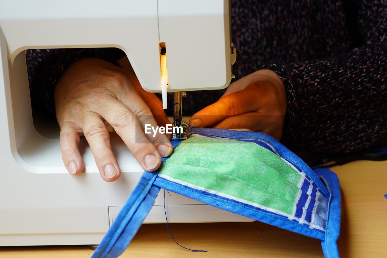 Hands of woman sewing a corona mask at sewing machine