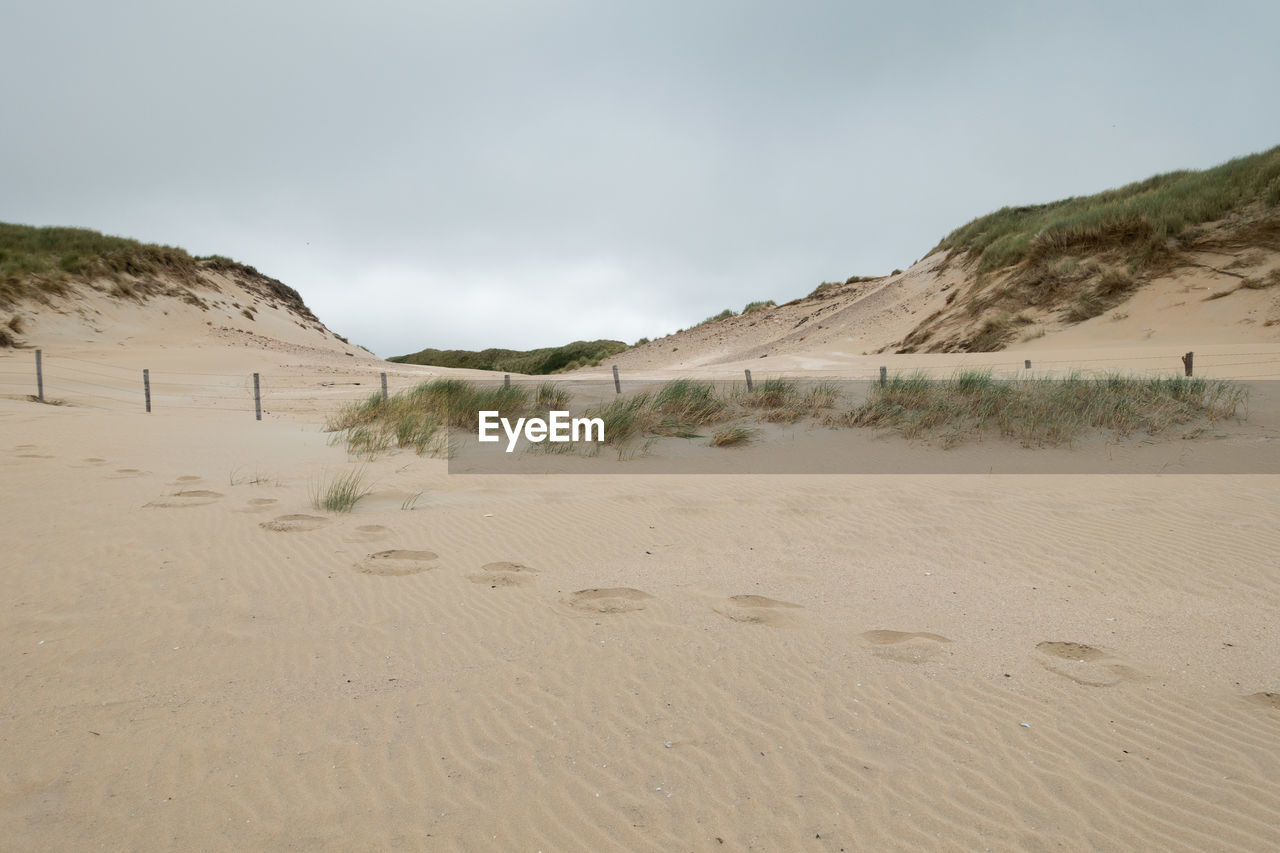 SCENIC VIEW OF SAND DUNES AGAINST SKY