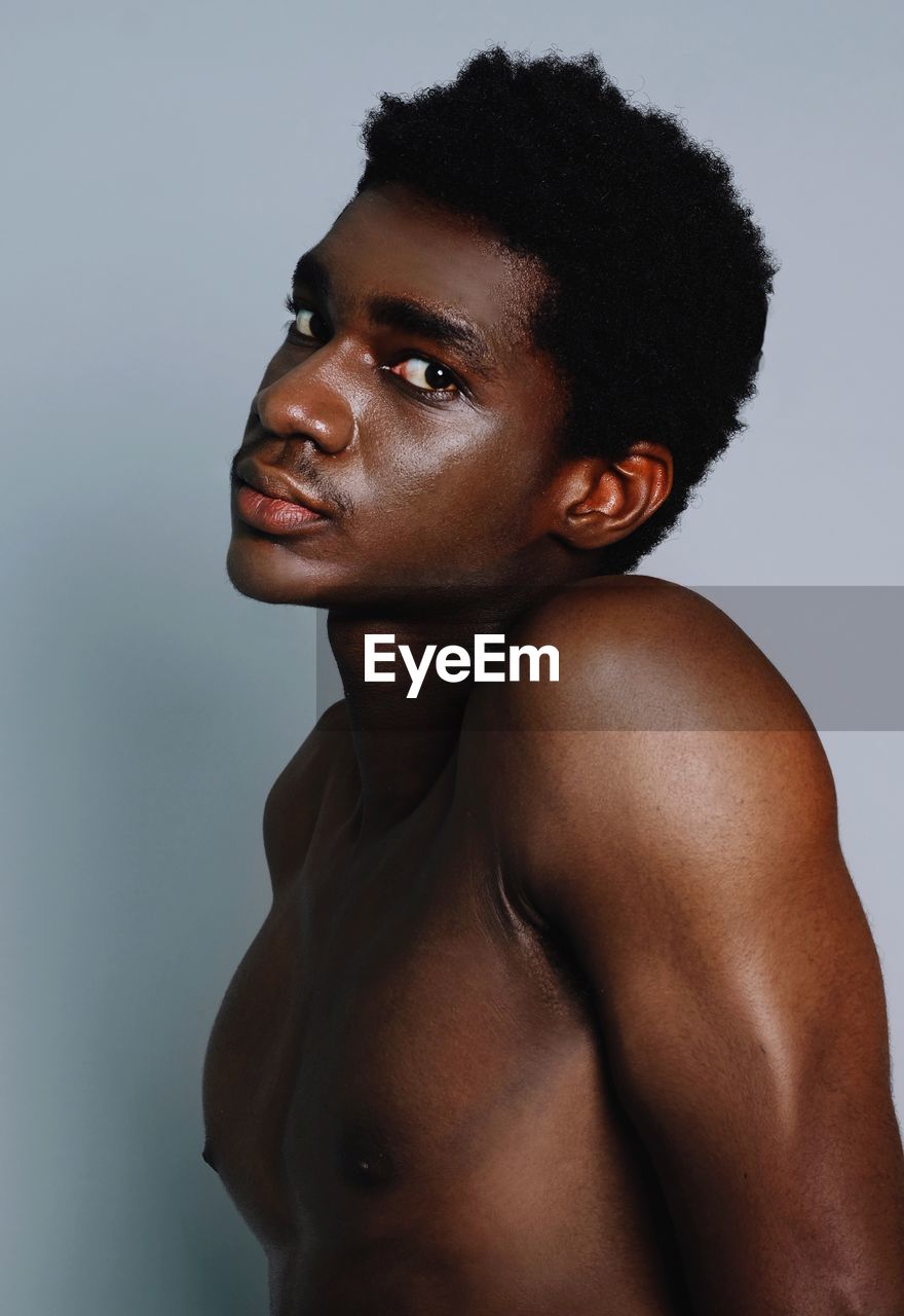 Portrait of shirtless young man against gray background