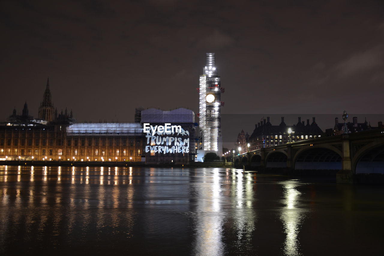 Reflection of illuminated bell tower on thames river in city at night