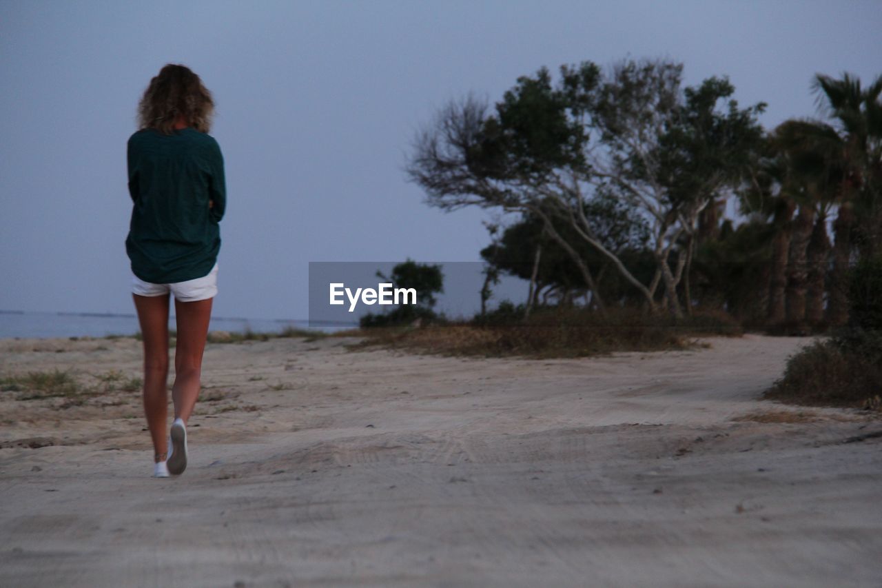 Rear view of woman walking at beach