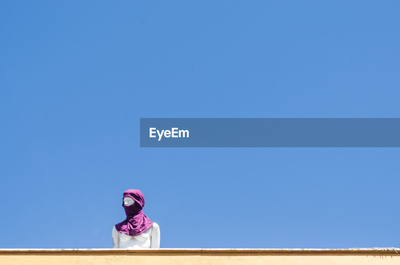 Low angle view of woman against clear blue sky